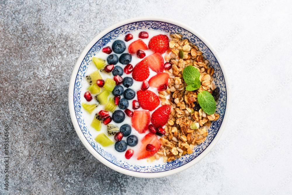 Breakfast smoothie bowl with fruits and granola. Superfood bowl isolated on concrete background. Clean eating, dieting, weight loss concept Breakfast smoothie bowl with fruits and granola. Superfood bowl isolated on concrete background. Clean eating, dieting, weight loss concept