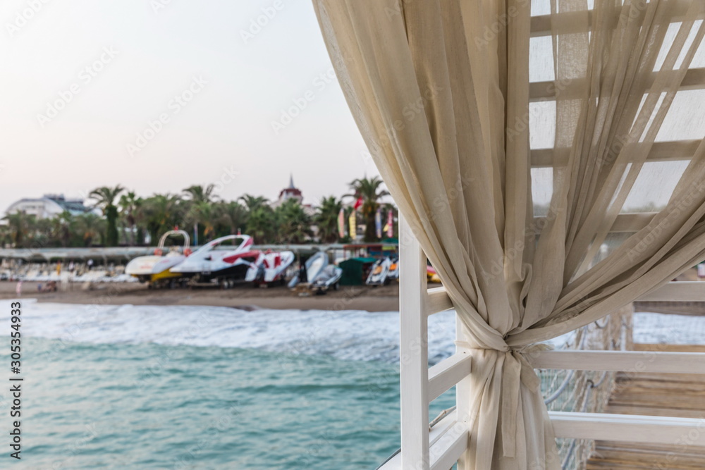 Fototapeta premium beige curtain on the background of the beach of the Mediterranean Sea at sunset