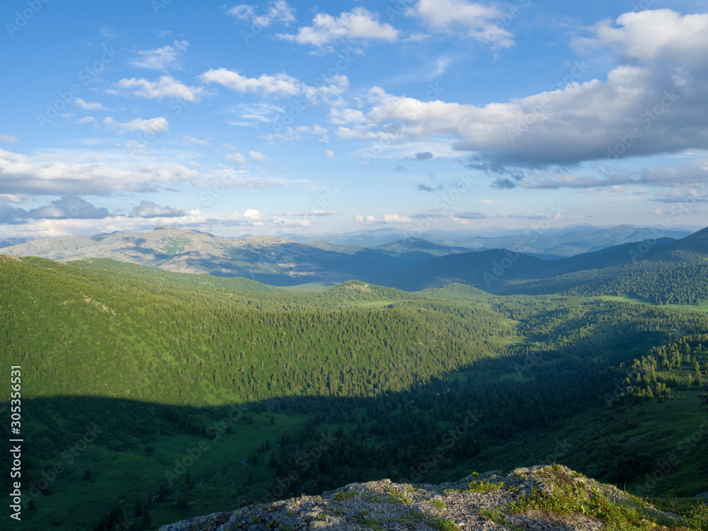 Panorama view from the top of the mountain to the green valley. Sunny day in the mountains of the Western Sayan