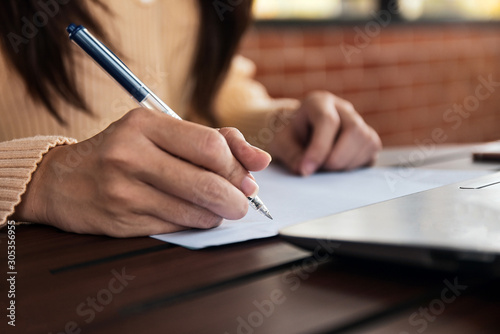 Businesswoman holding pen writing on paper document working,Close up hand write paperwork