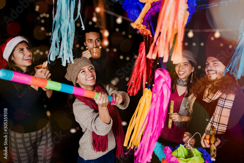Foto Posada Mexicana, Mexican friends breaking a Piñata and celebrating Christmas in
