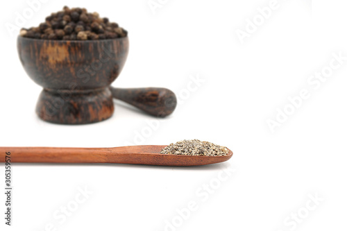 closeup the black pepper in Wooden mortar on white background , selective focus. Herbal Medicines.
