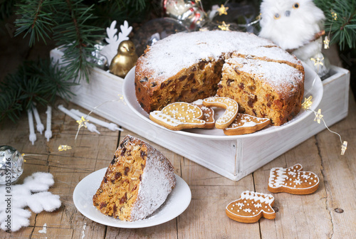 Traditional Christmas fruitcake on the background of a box with Christmas toys and fir branches.
