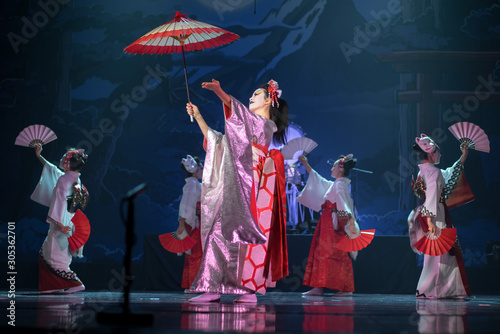 Traditional Japanese performance. Actresses in traditional white and red kimono and fox masks dancing with umbrella and fans.