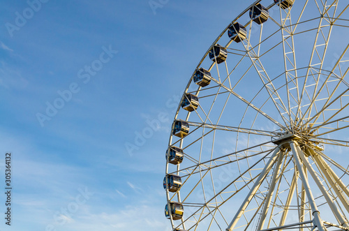 part of white ferris wheel against blue sky background