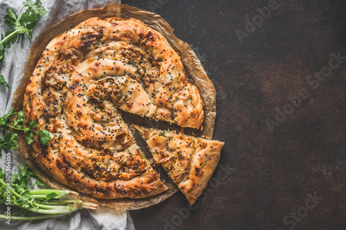 Turkish savory pie with Phyllo dough. Su boregi, burek or borek on dark rustic background. Top view. photo
