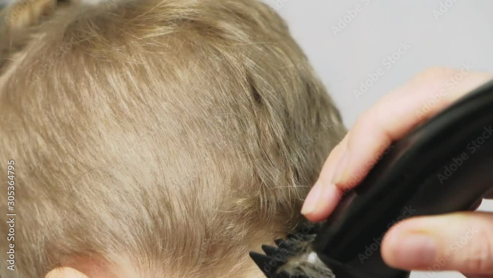 Close up of the boy's face with stylish haircut. Barber makes a hairstyle for a little boy in a male barbershop, haircut. Close up of the boy's face with stylish haircut. Barber makes a hairstyle for a little boy in a male barbershop, haircut.