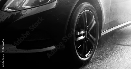 Reflecting everything around with its glossy surface, the premium car rides asphalt road where you can observe the suspension and how the tires perceive driving conditions. Black and white color gradi photo