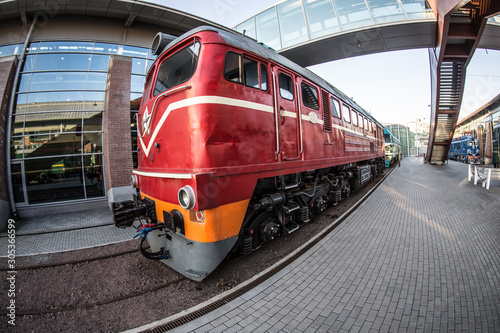 red locomotive on the platform of the railway station