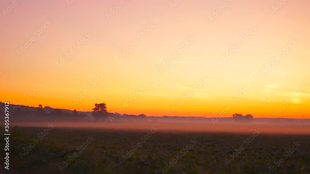 The Stunning Polish Landscape By The Road In Twilight With Light Fog, Trees And Orange Sky In Background - Wide Panning Shot The Stunning Polish Landscape By The Road In Twilight With Light Fog, Trees And Orange Sky In Background - Wide Panning Shot