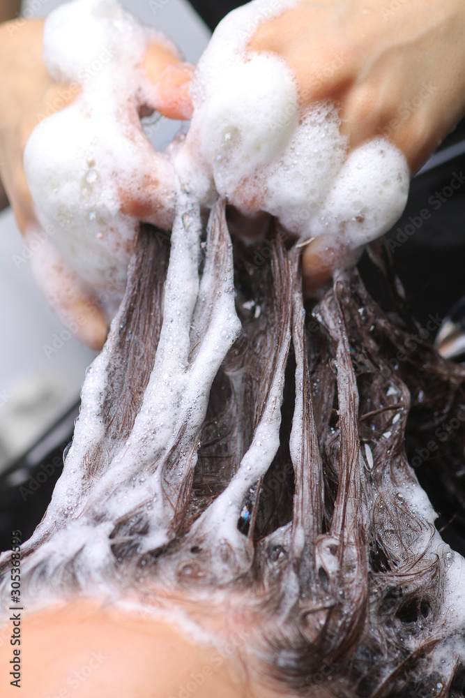 Obraz premium Hairdresser washing woman's hair in hairdresser salon