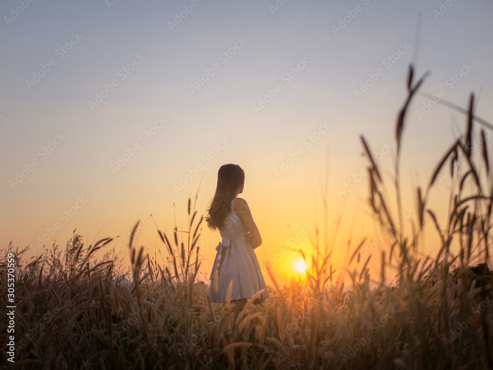 Trendy girl in stylish summer dress feeling free in the field with flowers in sunshine,enjoying nature, Beautiful Teenage Model in the Spring Field, Sun Light.