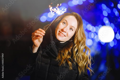 Woman with sparkler outdoors in winter.
