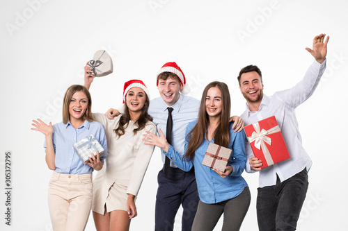Happy Christmas friends wearing Santa hats with gifts in hands on a white background.