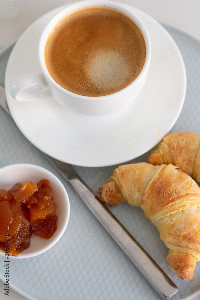 breakfast with a cup of coffee croissants and jam