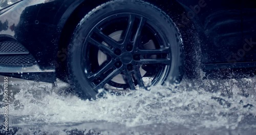 A large stream of spray erupts from under the wheels, flying far around. Slow mo, slo mo, slow motion, high speed camera Phantom