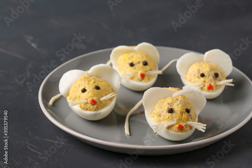 Festive snack Mice for 2020 made of stuffed eggs with cod liver on a dark background, Symbolic food for the new year, horizontal orientation © Anzhela