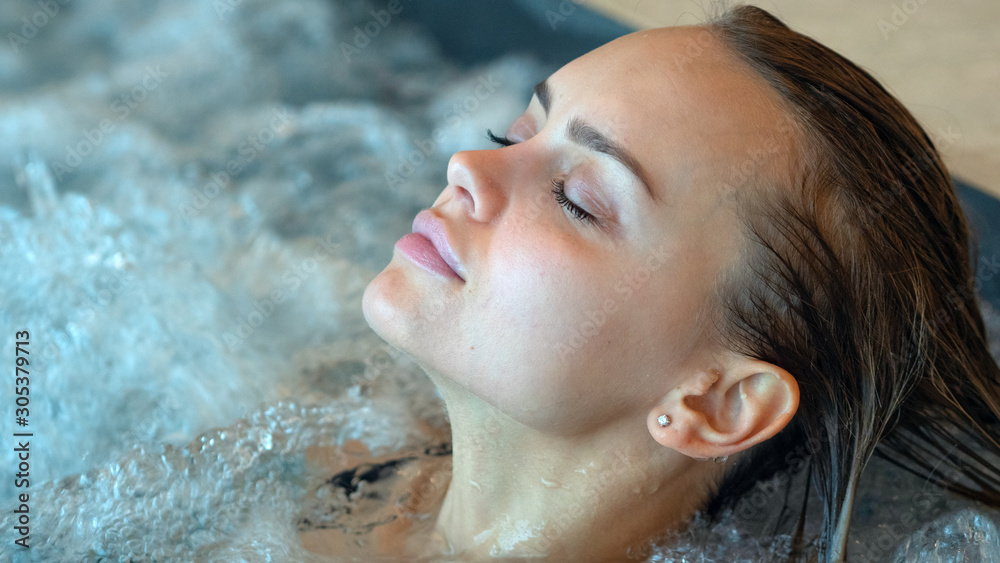 Close up of an young female is enjoying and having relax in a whirlpool bath tube in a luxury wellness center.