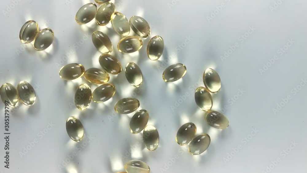 Transparent golden pills laying on a white table, SLIDE OVERHEAD Transparent golden pills laying on a white table, SLIDE OVERHEAD