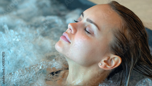 Close up of an young female is enjoying and having relax in a whirlpool bath tube in a luxury wellness center. photo