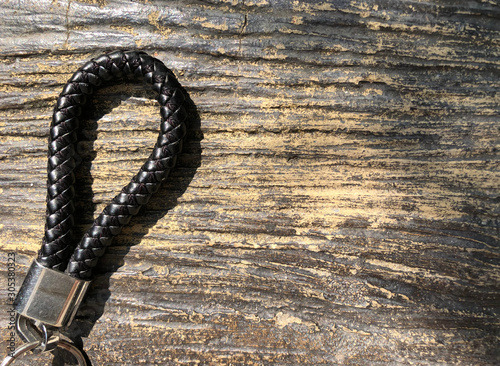 Picture of Black Leather Keychain on wood texture in dark brown tone