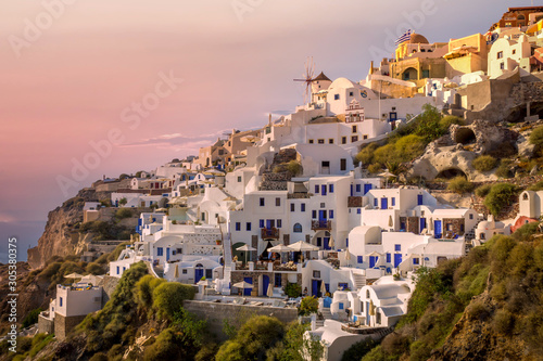 Little houses in the cliff at the city of Oia in Santorini, Greece. .Pink skies fills the skyTravel, city, explore, and summer concept.