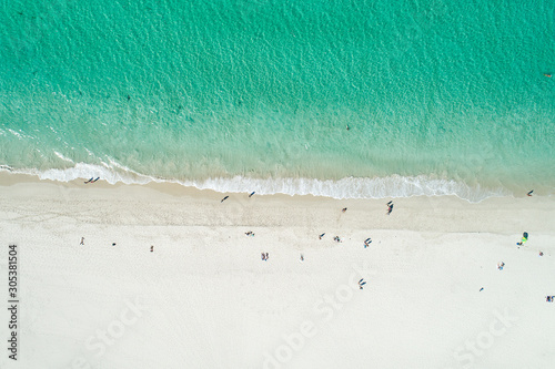 Aerial drone view of sandy white beach in summer with brilliant blue turquoise waters