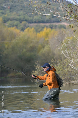 fly fisherman in river in autumn