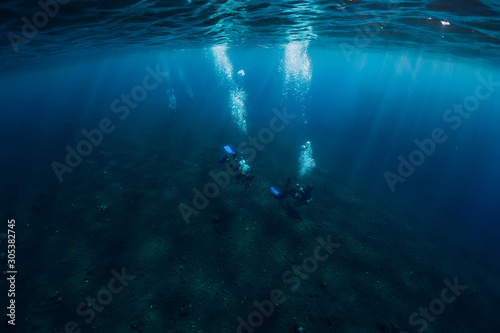 Divers underwater at shipwreck in Bali. Diving in sea