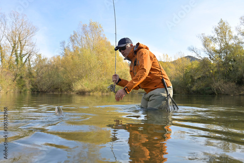 capture of a trout by a fly fisherman in autumn