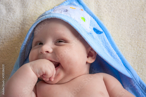 Portrait of a cute little smiling boy of 3 months in a blue towel.