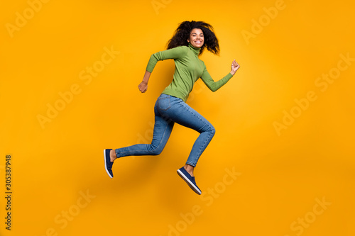Fototapeta Naklejka Na Ścianę i Meble -  Side profile full length body size photo of positive cute nice girl running jumping to shopping mall for discount in jeans denim green sweater isolated vivid color background