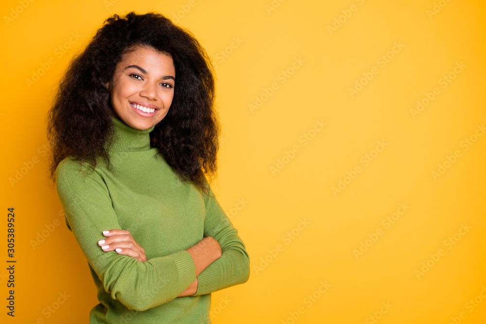 Fototapeta premium Photo of cheerful positive curly wavy cute nice pretty girl smiling toothily with hands folded near empty space isolated vibrant color background