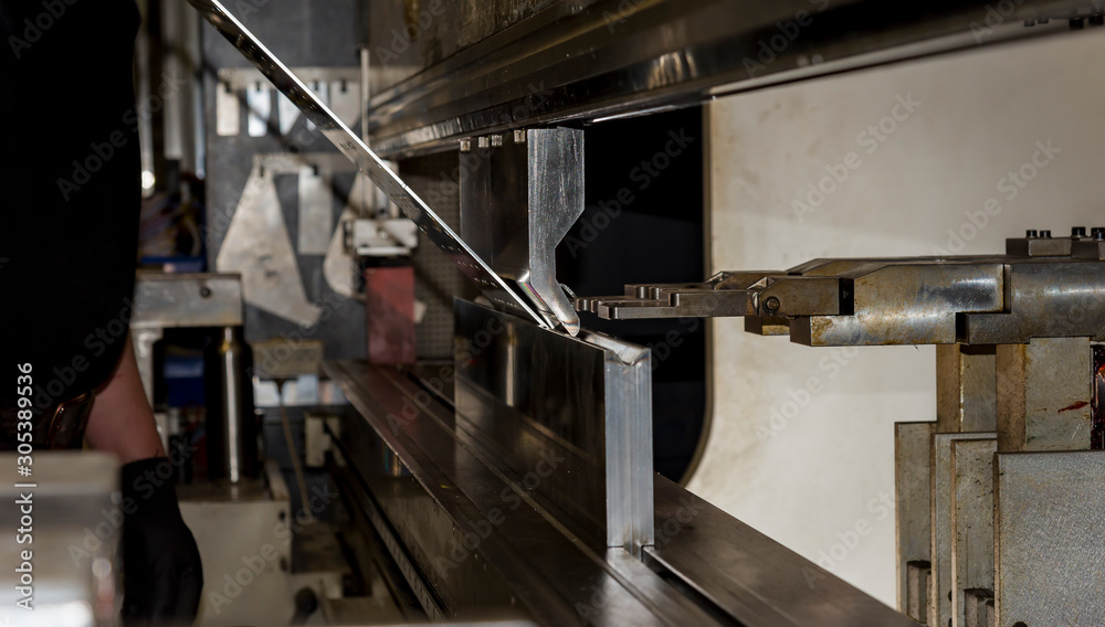 Fototapeta premium worker operating metal press machine at workshop.