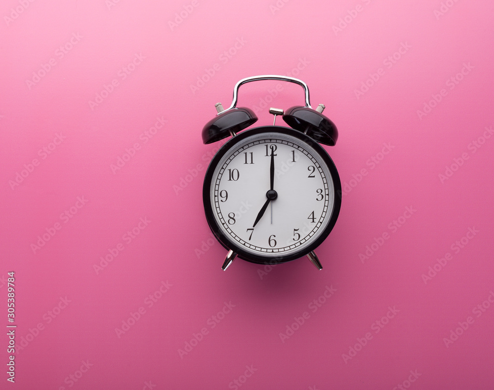 Alarm clock on pink background top view. Seven o'clock. Alarm clock on pink background top view. Seven o'clock.
