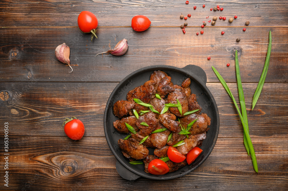 Homemade chicken liver fried with soy sauce, tomatoes, onions and spices on wood background. Top view Homemade chicken liver fried with soy sauce, tomatoes, onions and spices on wood background. Top view