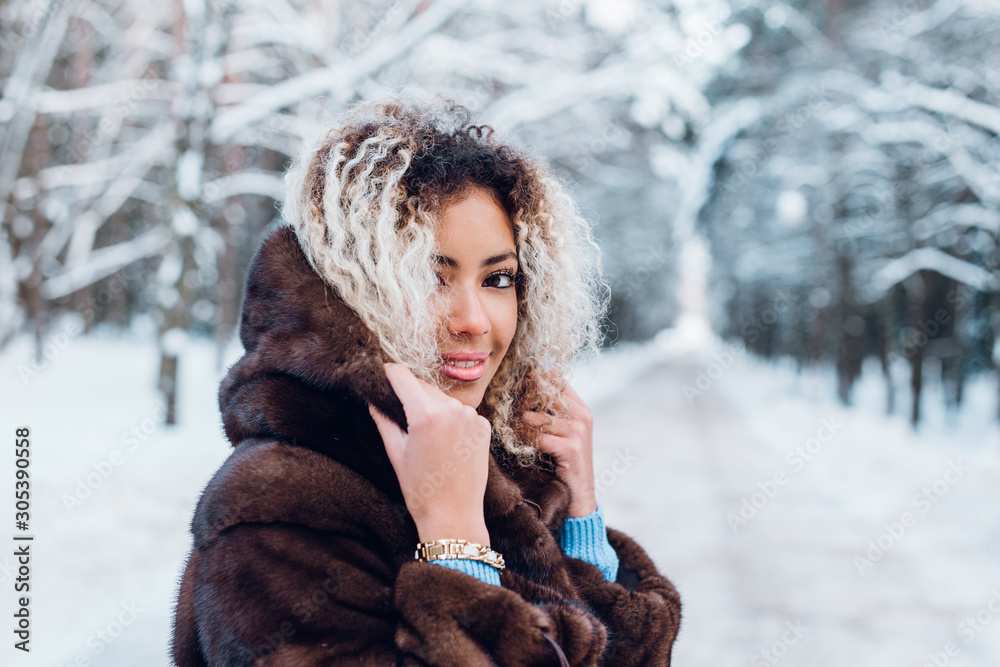 Smiling afro american girl wearing in fur coat in winter park Smiling afro american girl wearing in fur coat in winter park