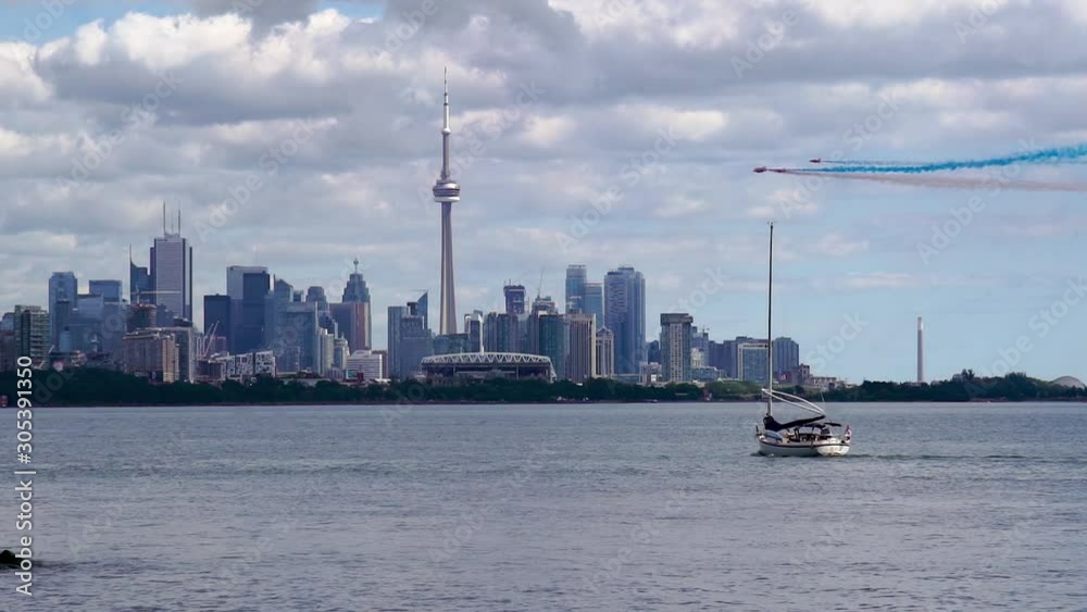 Toronto, Ontario, Canada - A boat is moving across the waters while above are five planes did fantastic movement in the air with the smoke of blue and red - Wide shot Toronto, Ontario, Canada - A boat is moving across the waters while above are five planes did fantastic movement in the air with the smoke of blue and red - Wide shot