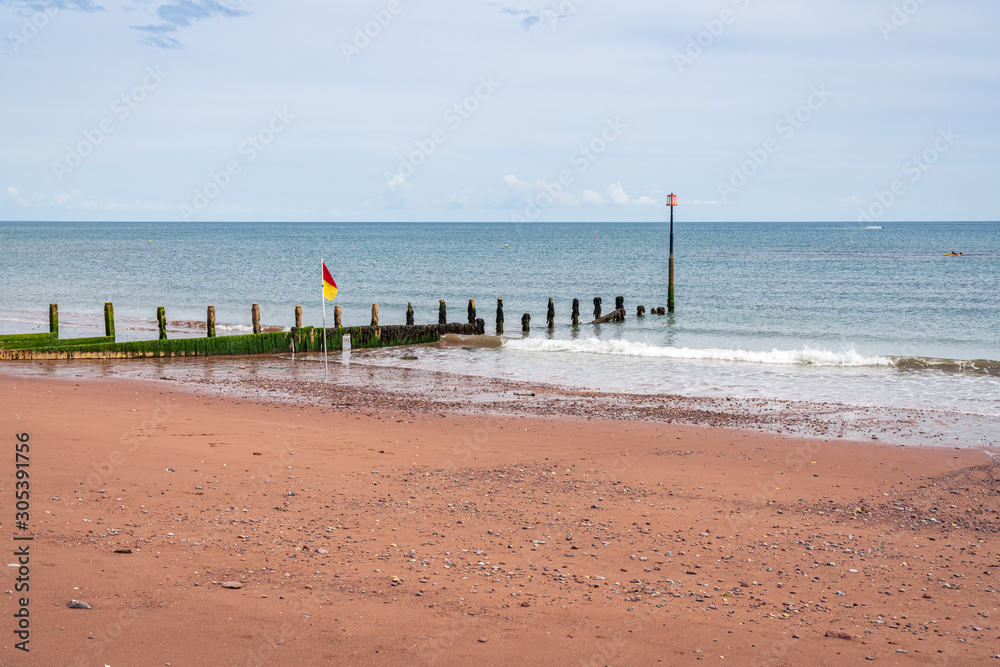 A groyne and a flag on the beach in Teignmouth, Devon, England, UK