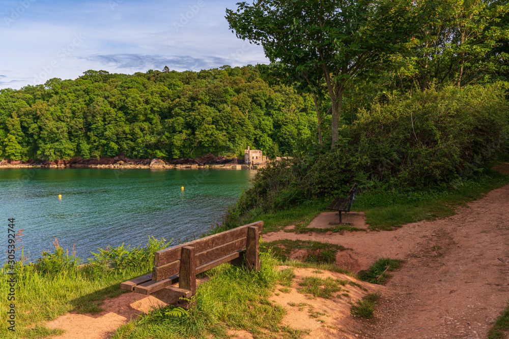 Fototapeta premium Walking towards Elberry Cove, Torbay, England, UK - with the disused bath-house on the edge of the shingle beach