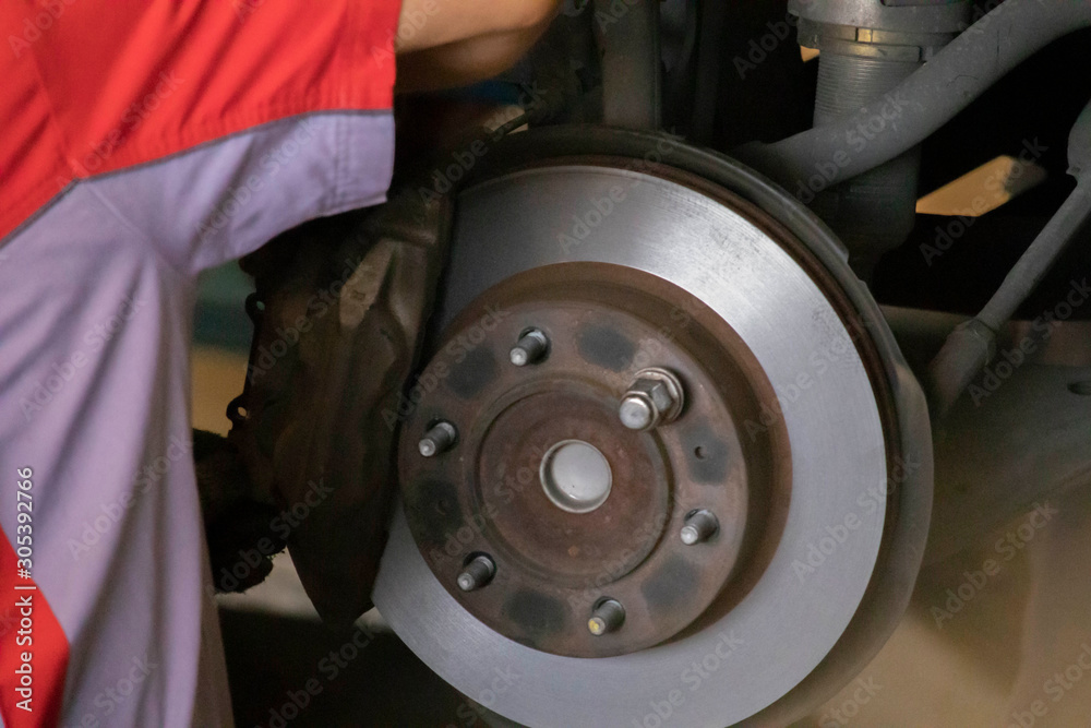 The mechanic is cleaning the front wheel brake set of the car before changing to a new wheel. The mechanic is cleaning the front wheel brake set of the car before changing to a new wheel.