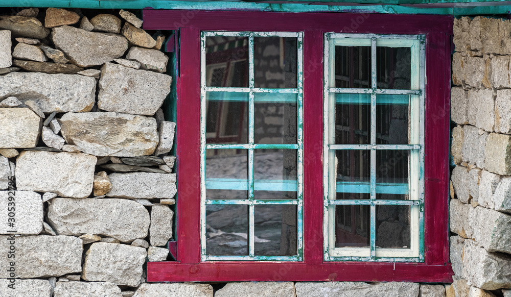 Stone wall with grunge window in a mountain hut