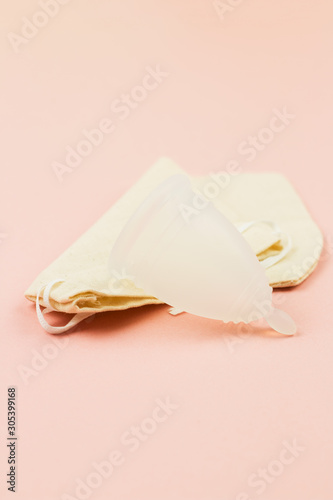 Close up of menstrual cup in cotton bag on pink background
