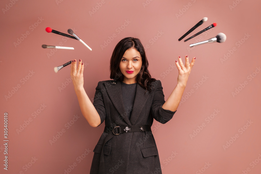 Studio photo of makeup artist woman smiling and throws up brushes