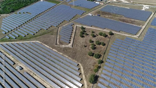 Aerial footage moving over photovoltaic station also known as a solar park or farm is large-scale PV system designed for the supply of merchant power into the electricity grid by sunlight 4k quality photo