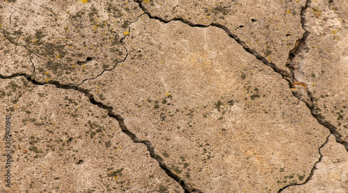Cracked concrete texture closeup. Abstract cement background. Old concrete cement with cracks and natural destruction from time and weather conditions.
