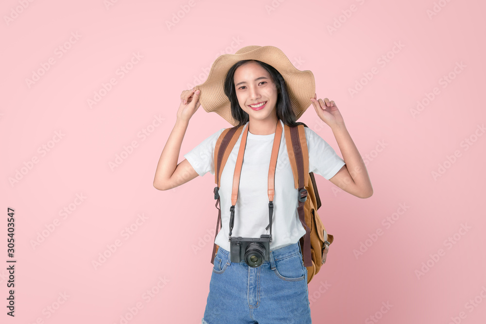 Attractive young Asian woman traveler standing touching hat on head, camera and look photo on pink background. Attractive young Asian woman traveler standing touching hat on head, camera and look photo on pink background.