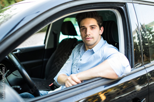 Concentrating on the road. Young handsome man looking straight while driving a car