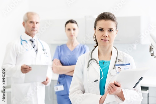 Portrait of confident doctors with medical reports standing at clinic