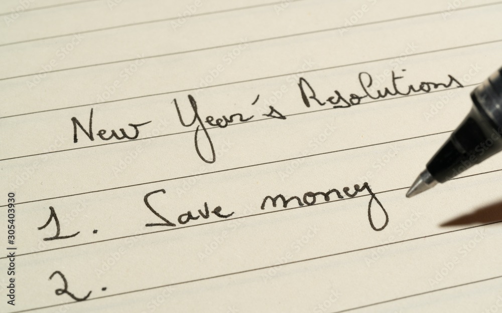 New Year's Resolutions list concept with someone completing a list on a notebook with a pen close up shot New Year's Resolutions list concept with someone completing a list on a notebook with a pen close up shot
